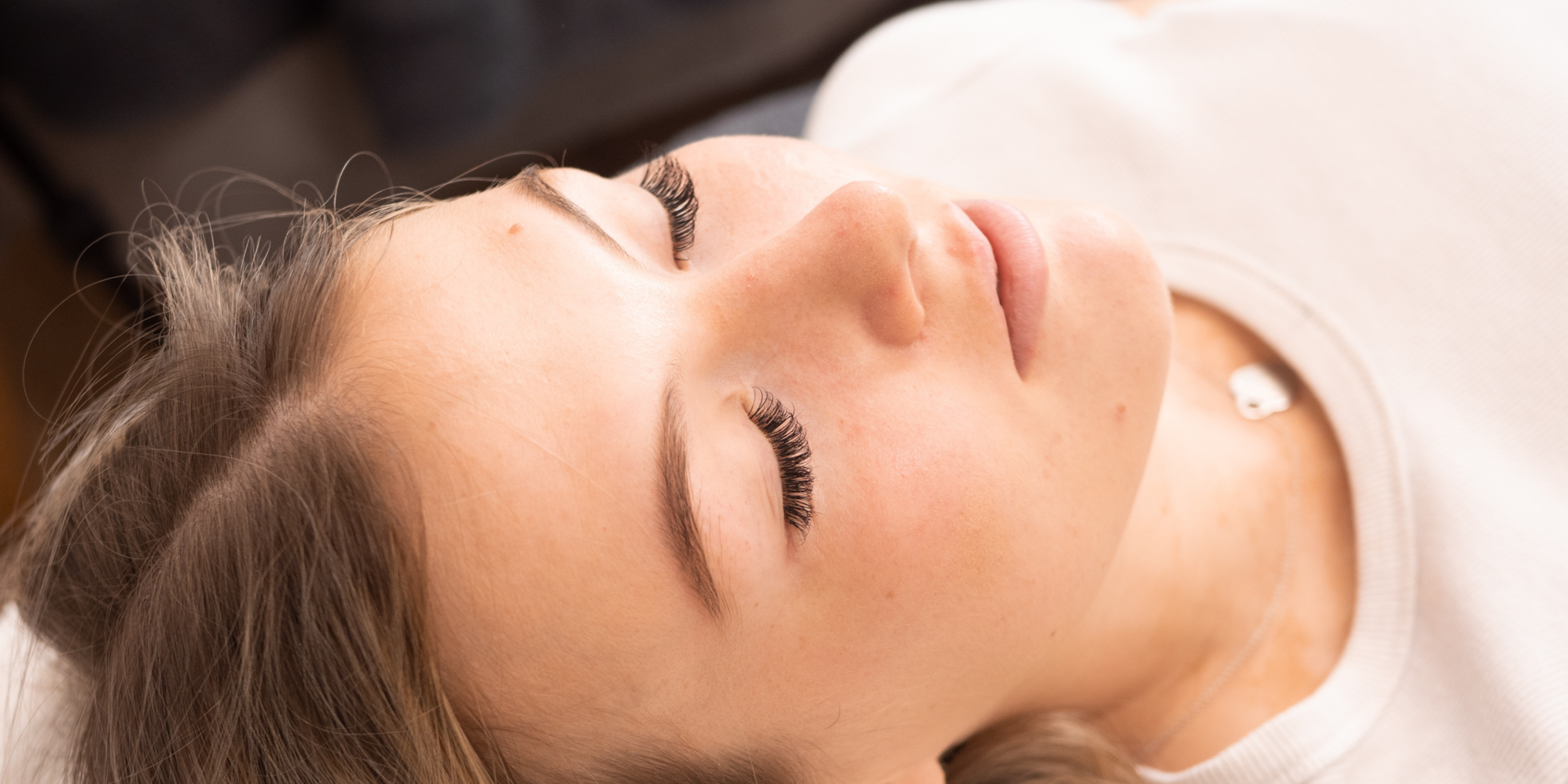 woman with a fresh set of eyelash extensions laying down with her eyes closed